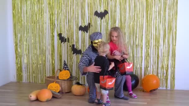 Scary man with Halloween costume hold his children son and daughter on knees — Stock Video