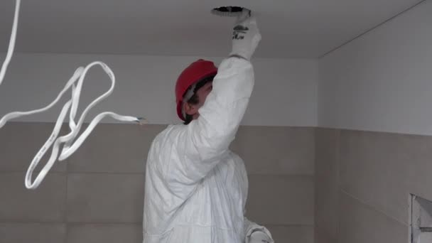 Muž elektrikář se speciálním oblečením práce na LED osvětlení v novém bytě. 4K — Stock video