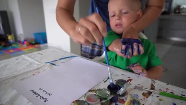 Mamma och småbarn gör handavtryck med akvarell på papper. Gimbal rörelse — Stockvideo