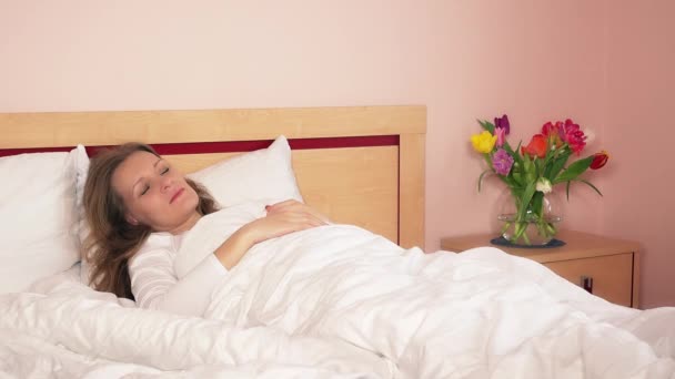 Fröhliches, kuscheliges Mädchen weckt seine junge Mutter im Bett. 4K — Stockvideo