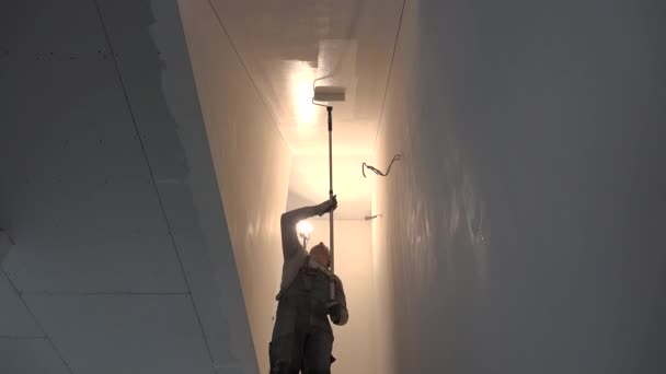 석고 천장을 페인트 롤러와 함께 계단에 칠하는 사람 — 비디오