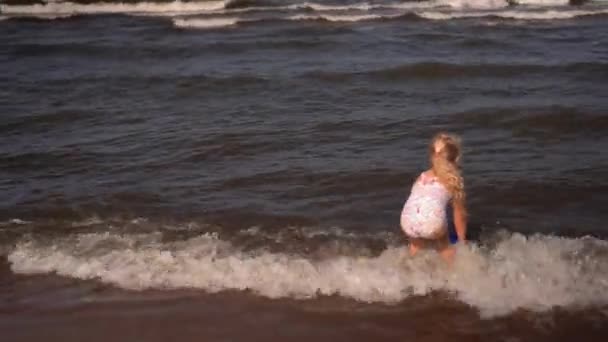 Дівчинка дошкільнята лопатою морської води з іграшковим відром і носінням . — стокове відео
