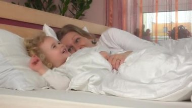 Mutlu anne ve iyi kız birbirlerini beyaz yatak ile gıdıklıyorlar. 4K