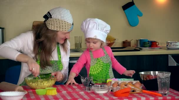 Мама смешивает тесто для печенья в миске и маленькая дочь смотреть и помогать. 4K — стоковое видео