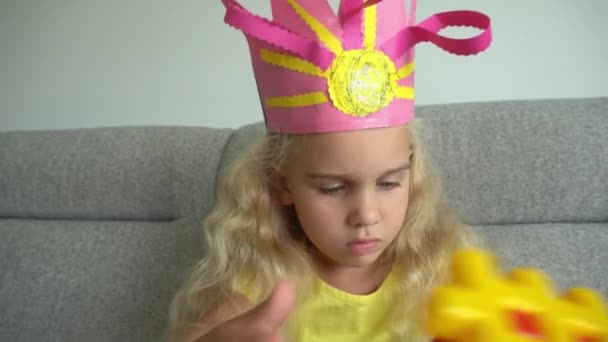 Prinses meisje met kroon spelen met kleurrijke delen op de bank. Gimbal beweging — Stockvideo