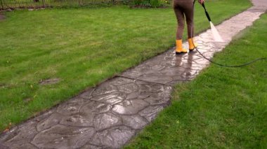 Kız bahçede su basıncıyla çalışıyor. Taş yolu yıkama. 4K