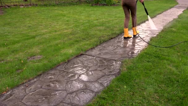 Chica de trabajo con la presión del agua en el jardín. Camino de piedra lavado. 4K — Vídeos de Stock