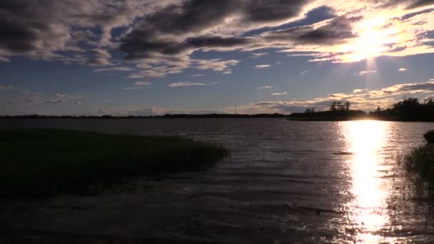 Красивый закат над озером и солнечные отражения на движущихся волнах — стоковое видео