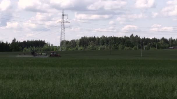 Tractor spray green summer corn field pesticide near wiring pole — Stock Video