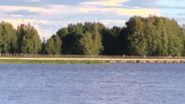 insanlar ahşap uzun köprüde göl üzerinde yürümek ve ağaç yaprakları