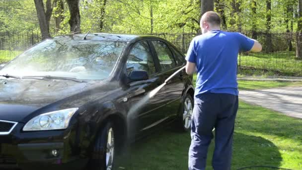 Ouvrier laver voiture noire en plein air avec équipement d'eau à haute pression — Video