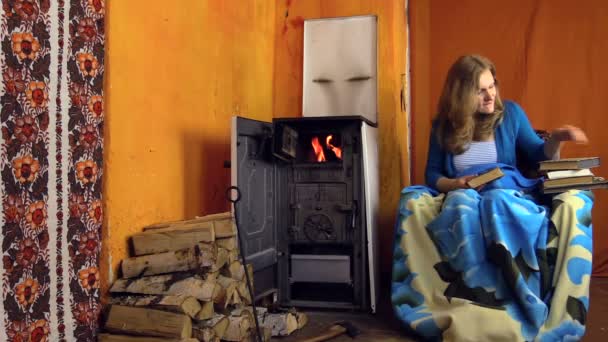 Young girl found interesting book and read near to the stove — Stock Video