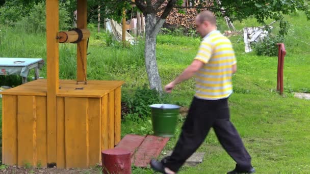 Young man turning old rural yellow well handle in countryside — Stock Video