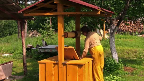 Gammal bybo kvinna på, dra vatten och häll det hink — Stockvideo