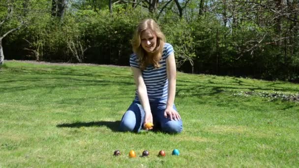 Девушка весело провести время, играя в пасхальные игры с окрашенными красочными яйцами — стоковое видео