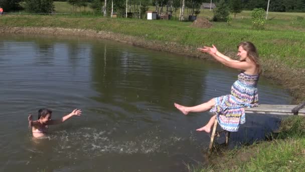 Glad tjej simma och plaska gravid mamma kvinna på bron — Stockvideo