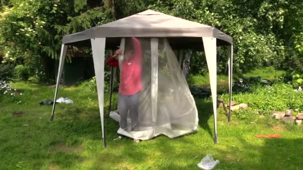 Man attach protective tent bower net in garden — Stock Video