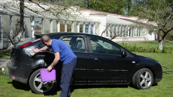 Man met emmer water van de zeep en spons schoon favoriete auto — Stockvideo