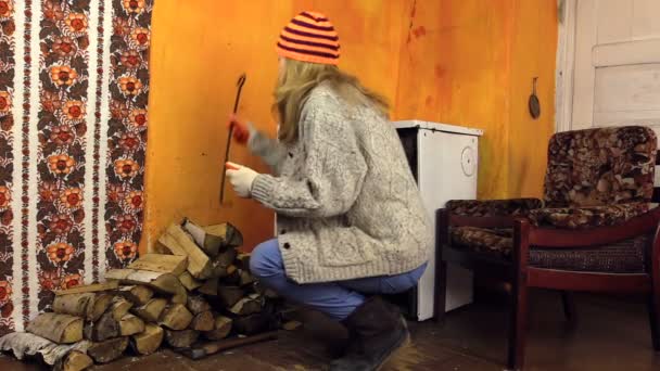 Menina aberta porta do forno de banhos sentado na cadeira pelo fogo na sala rural — Vídeo de Stock