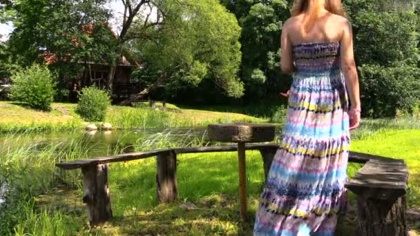 Gravid blondin tjej sitta i parken solsken på träbänk — Stockvideo