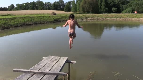 Young girl jump to pond water from wooden bridge in hot day — Stock Video