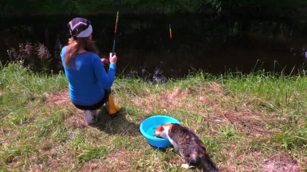 バケツの水から湖の海岸と猫キャス魚釣りの女性 — ストック動画