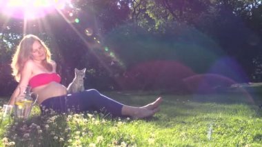 hamile kadın oyun kedi ile oturup güneşli park yonca çayır