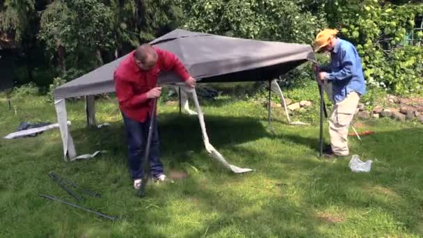 People stand garden tent bower roof on long metal legs — Stock Video