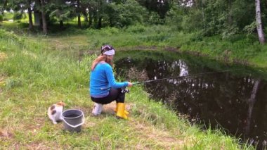 hamile kadın sarışın sevimli kedi ile göl kıyısında balık yakalamak