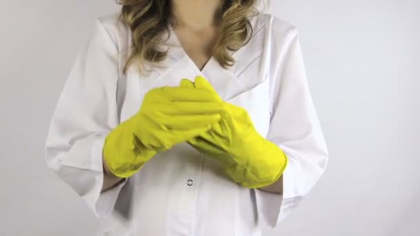 Vrouw in witte robe opstijgen haar handen gele rubber handschoenen — Stockvideo