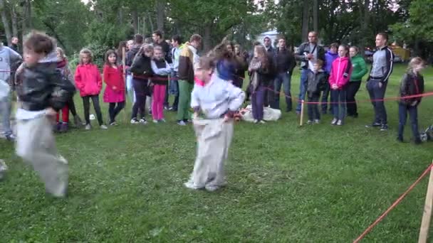 Aktive Kinder spielen Sackhüpfen im Stadtpark mit Publikum — Stockvideo