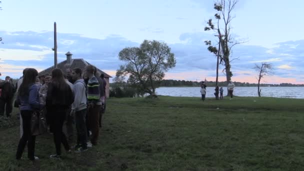 Crowd people around big log stacked campfire on field — Stock Video