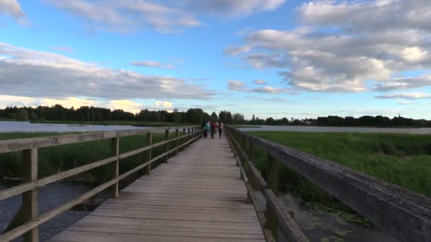 Teanager gå på träbro över sjön i kväll solljus — Stockvideo