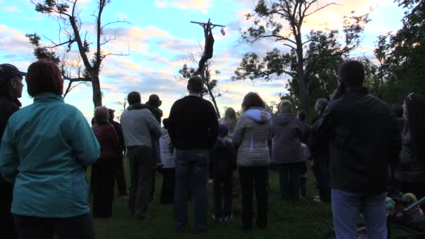 Люди смотрят на человека успешно взобраться на высокий бревенчатый столб получить приз — стоковое видео
