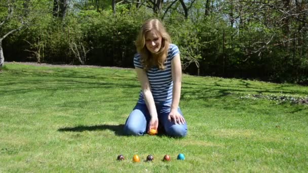 Jogo tradicional de Páscoa. Mão jogar rolar ovos coloridos na grama . — Vídeo de Stock