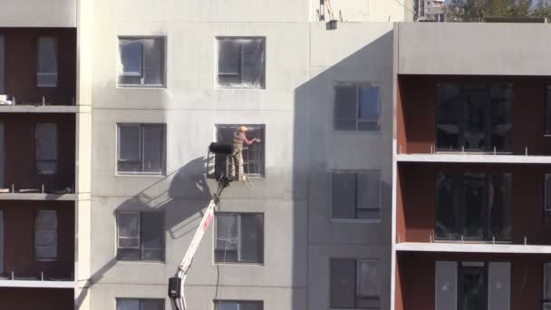 Рабочий человек распыляет тепловую белую краску на плоскую стену дома — стоковое видео