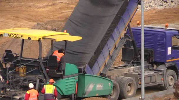 Les gens travaillent avec des machines de revêtement d'asphalte sur le chantier de construction — Video