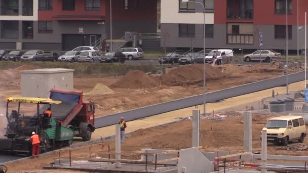 Zaměstnanci s těžkými stroji vydláždit asfalt u obytných domů — Stock video