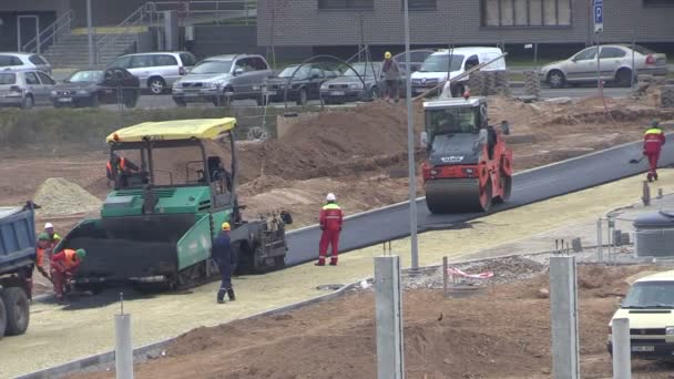 Persone lavorano su asfalto diffusione e rotolo marciapiede nel distretto piatto — Video Stock