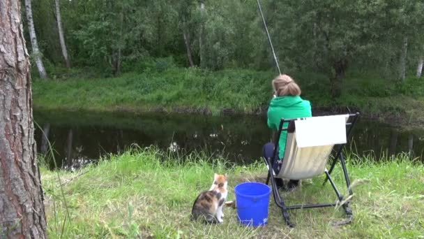 Kvinna fånga karp i landsbygdens damm. Hungrig katt vänta för fisk — Stockvideo