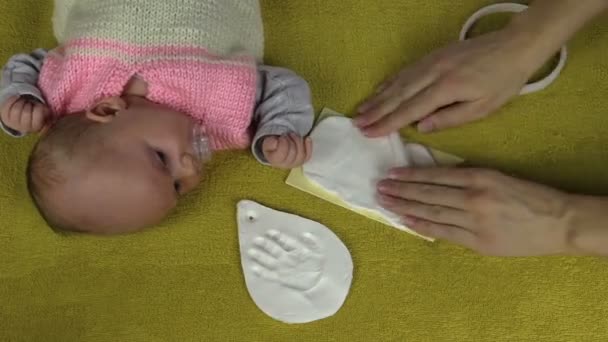 Mãos de mãe e mentira de bebê preparam material para pegada — Vídeo de Stock