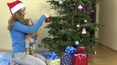Onun elinde yeni doğan bebek ile anne asmak Noel ağacı oyuncak