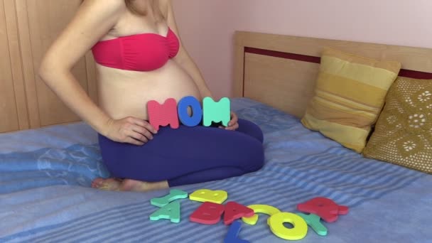 Pregnant woman hold word mom near her round big belly stomach — Stock Video