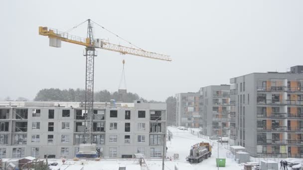 Jeřáb výtah betonového bloku house část a dělníci pracovat v zimě — Stock video