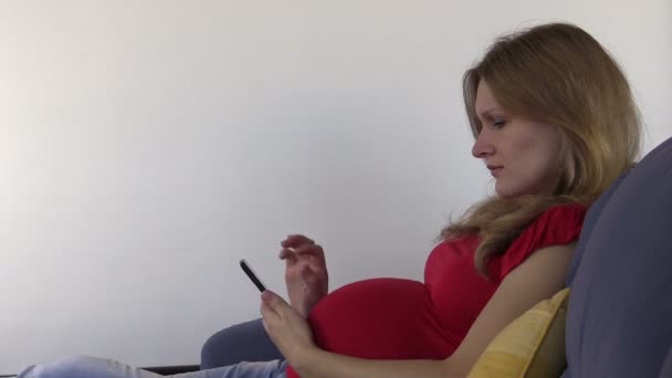 Cute pregnant woman browse photos and internet with smartphone — Stock Video