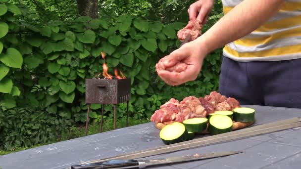 Man hands stab raw meat and zucchini pieces on spit. Fire burn — Stock Video