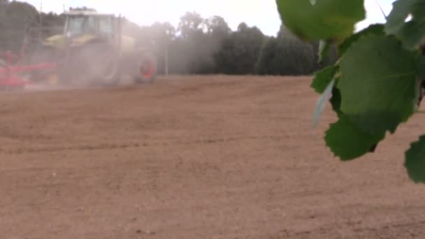 Abono de propagación del tractor en el campo cultivado. Las hojas del árbol se mueven — Vídeos de Stock