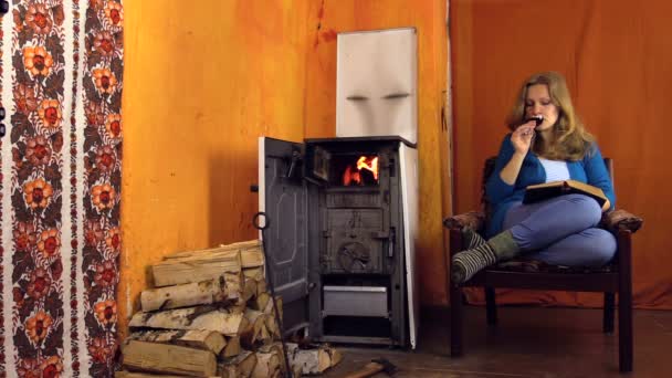 Woman sit in armchair with red wine in hand and read book — Stock Video