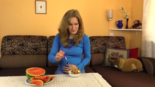 Mulher grávida acaricia a barriga e come salada de frutas frescas — Vídeo de Stock