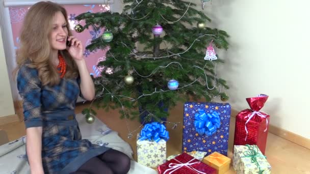 Mujer feliz cerca del árbol de Navidad hacer llamada de teléfono inteligente — Vídeos de Stock